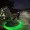 Alien spaceship costume on wheels glowing green with fog at night