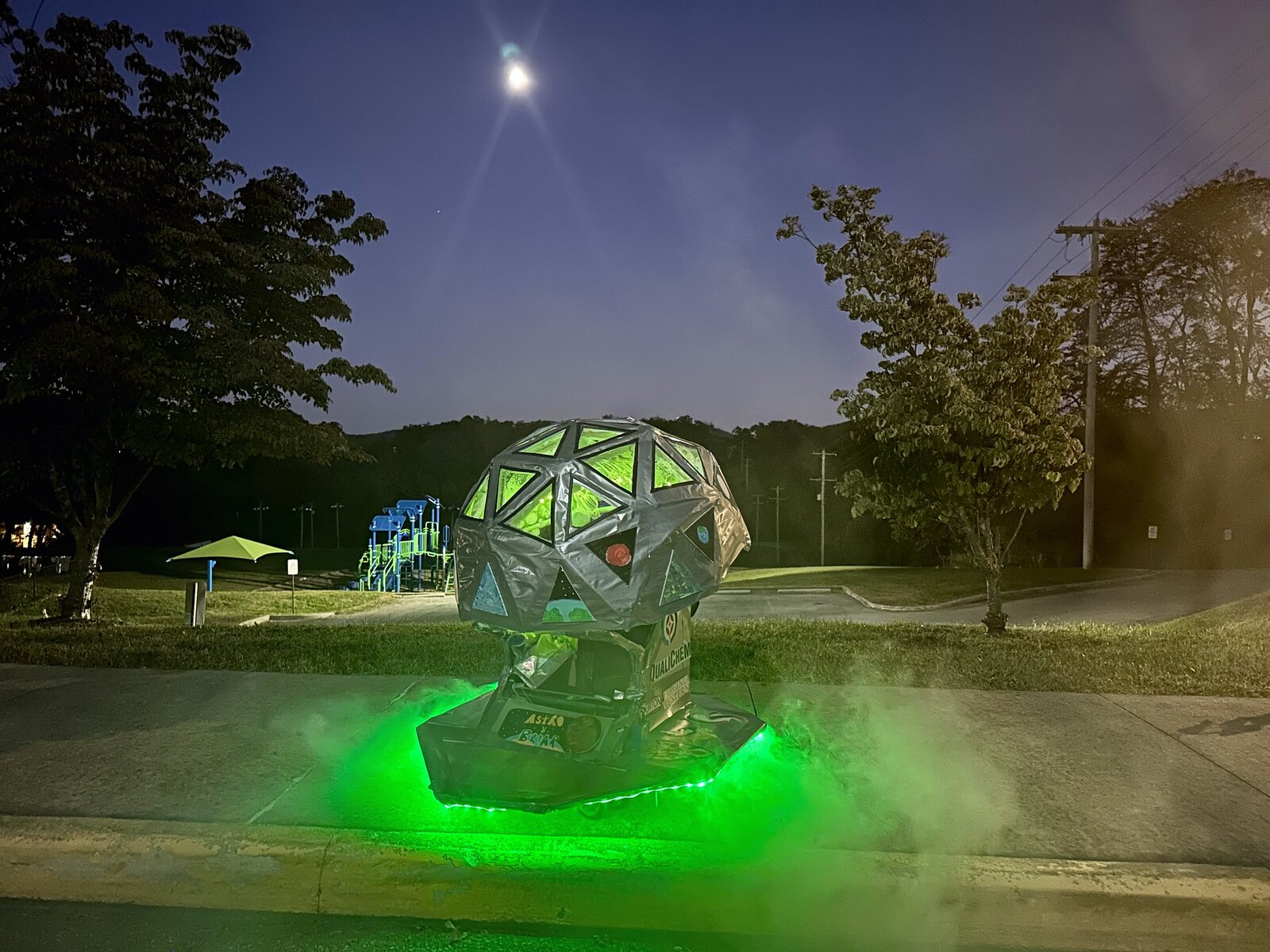 Alien spaceship costume on wheels lit green under the moon