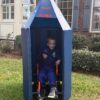 Child in a Dr. Ryland Grace astronaut costume inside a rocket ship on wheels