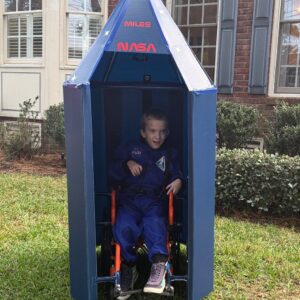 Child in a Dr. Ryland Grace astronaut costume inside a rocket ship on wheels