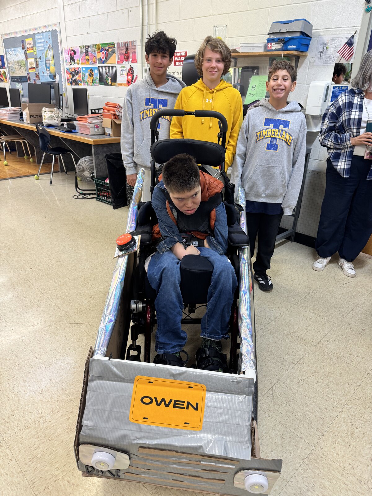 Child in a Back to the Future costume on wheels with the Timberlane Middle School students who built it