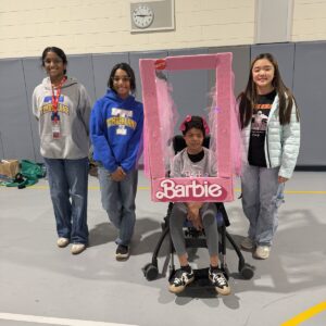 Child in a Barbie costume on wheels with the Timberlane Middle School students who built it