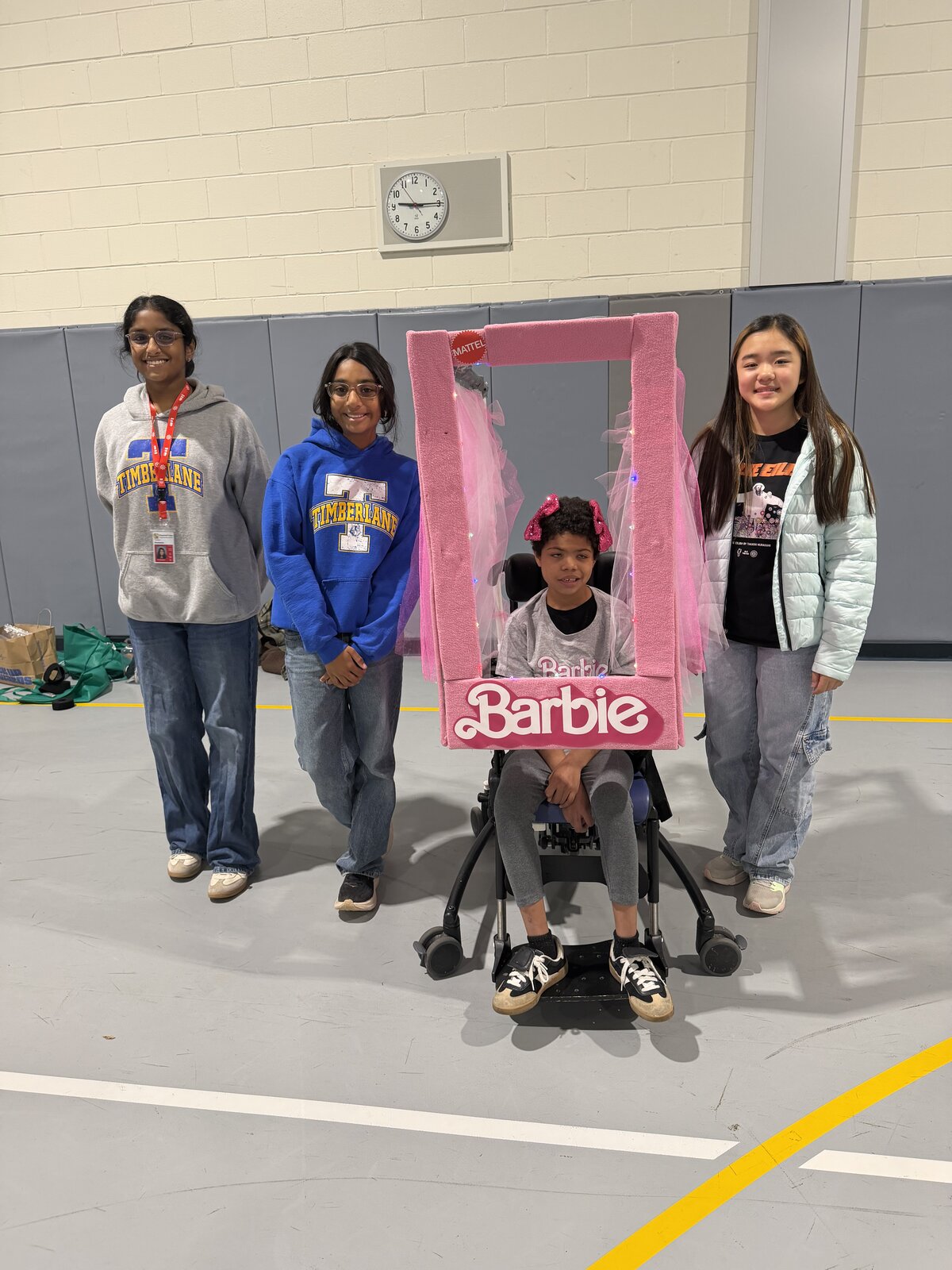 Child in a Barbie costume on wheels with the Timberlane Middle School students who built it