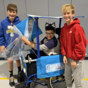 Child in a Bluey costume on wheels with the Timberlane Middle School students who built it