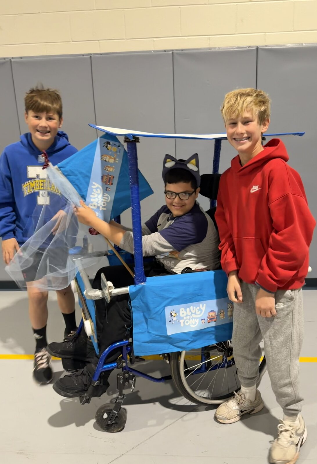 Child in a Bluey costume on wheels with the Timberlane Middle School students who built it
