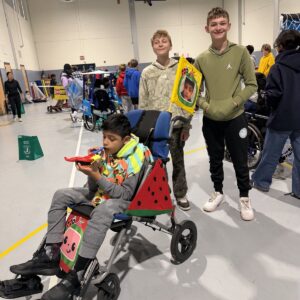 Child in a Cocomelon costume on wheels with the Timberlane Middle School students who built it