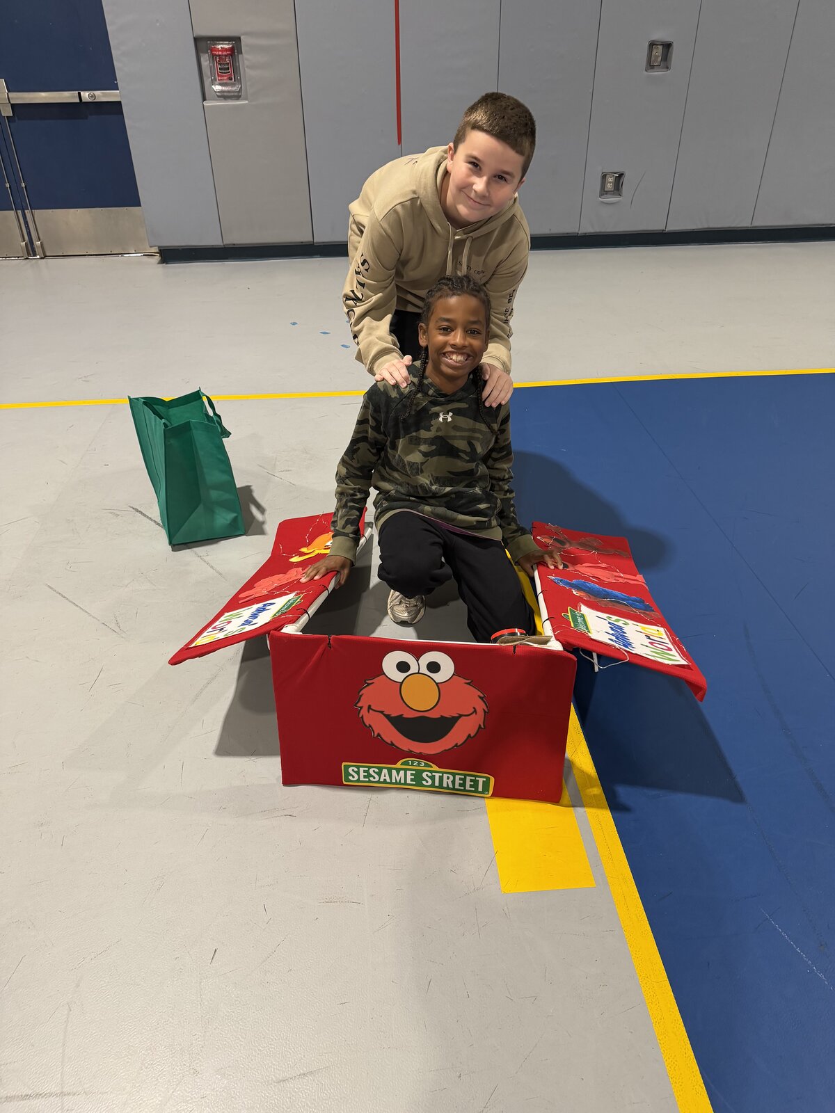Child in an Elmo's World costume on wheels with the Timberlane Middle School students who built it