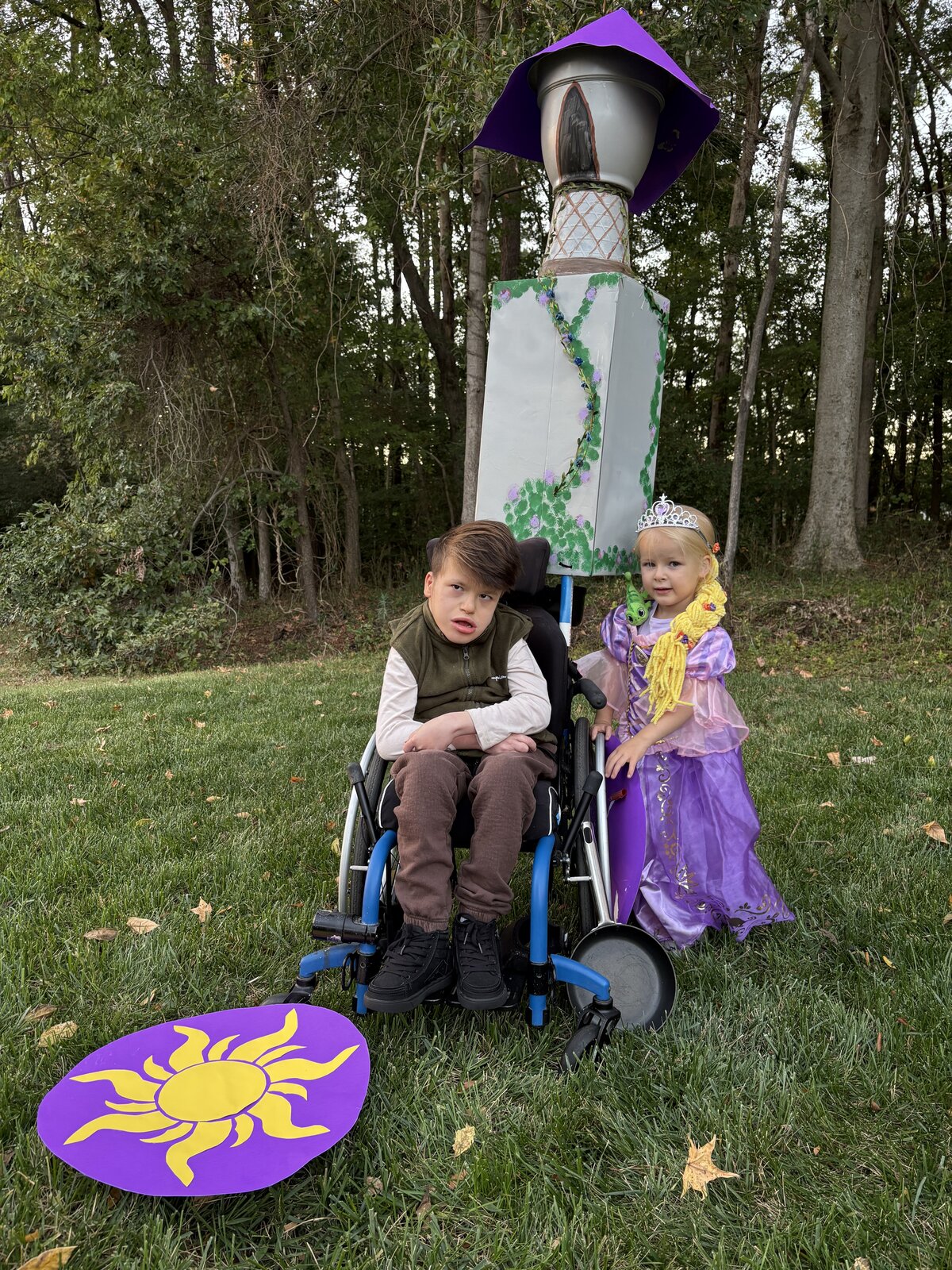 Child in a Flynn Rider with the Rapunzel Tower costume on wheels