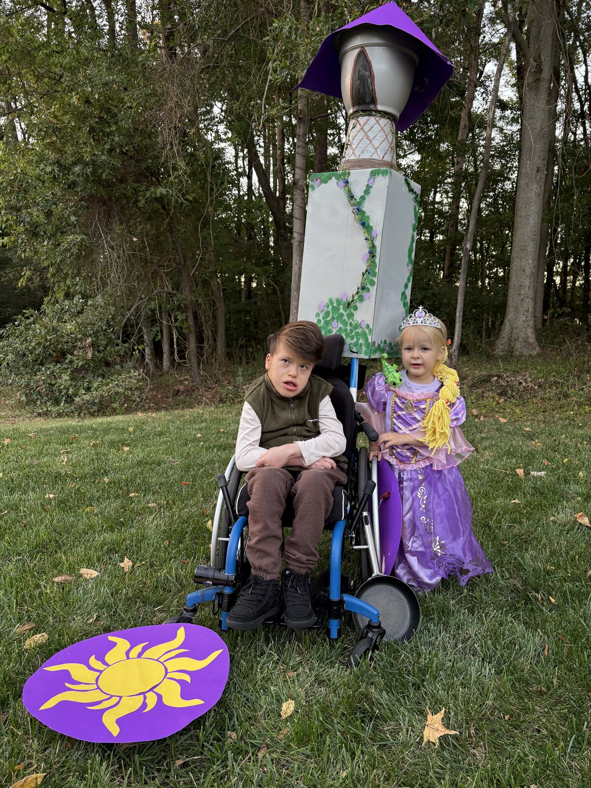 Child in a Flynn Rider with the Rapunzel Tower costume on wheels