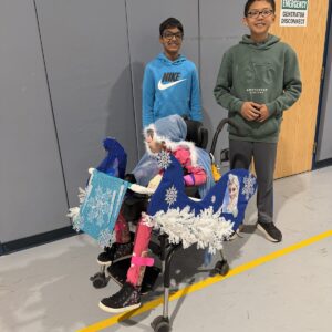 Child in a Frozen costume on wheels with the Timberlane Middle School students who built it