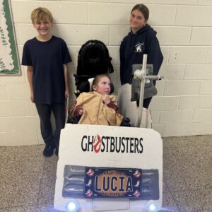 Child in a Ghostbuster costume on wheels with the Timberlane Middle School students who built it
