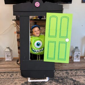 Child in a Mike Wazowski costume on wheels