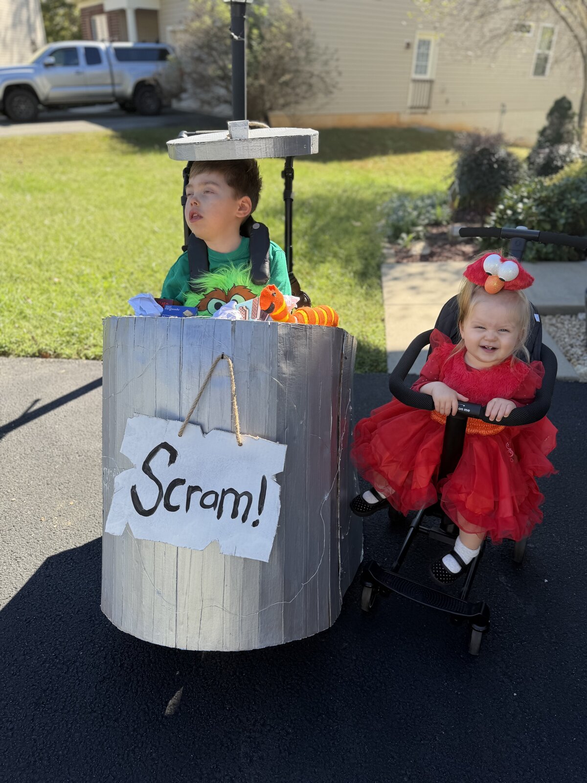 Child in an Oscar the Grouch and Elmo costume on wheels