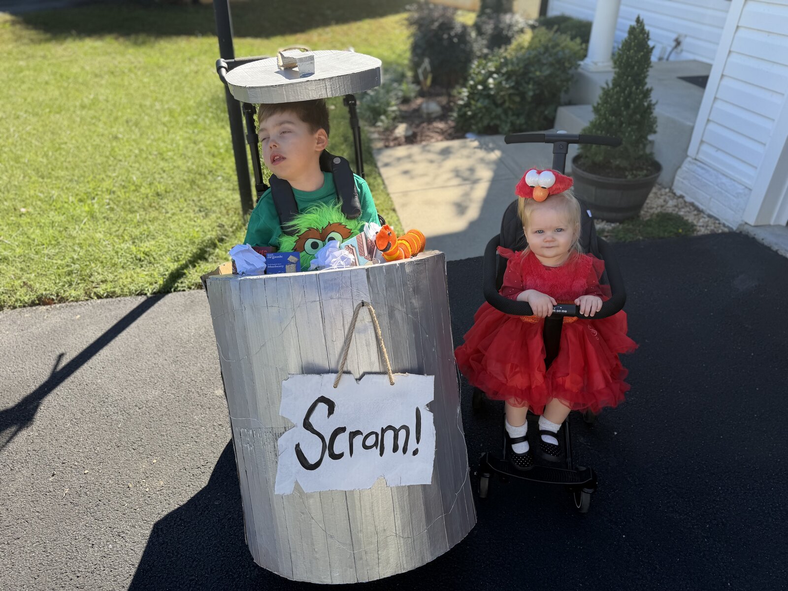 Child in an Oscar the Grouch and Elmo costume on wheels
