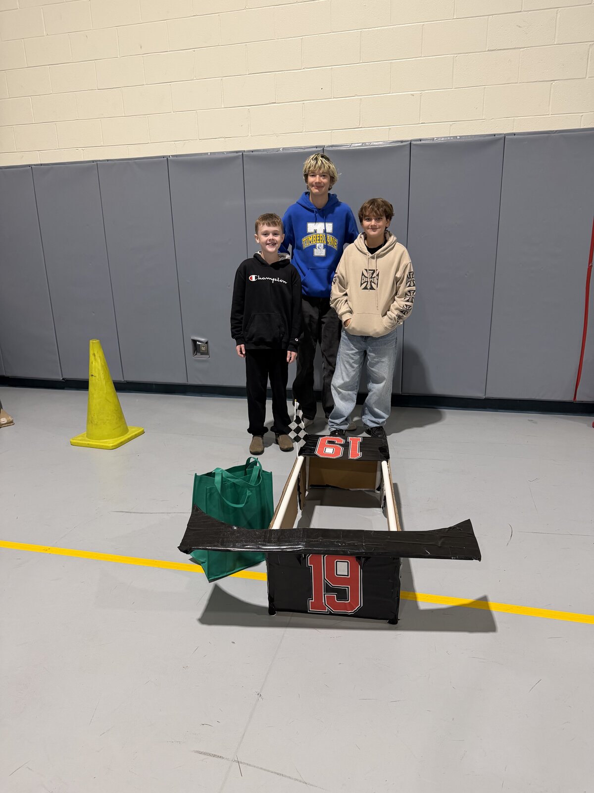 Child in a Race Car costume on wheels with the Timberlane Middle School students who built it