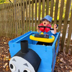 Child in a Thomas the Train costume on wheels