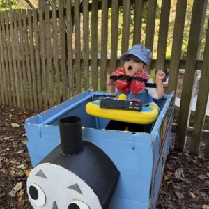 Child in a Thomas the Train costume on wheels