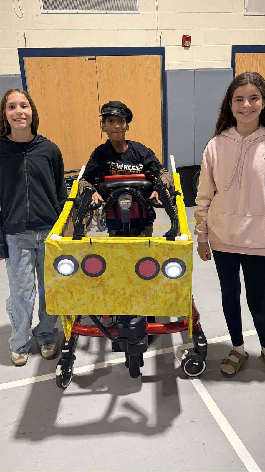 Child in a Wheels on the Bus costume on wheels with the Timberlane Middle School students who built it