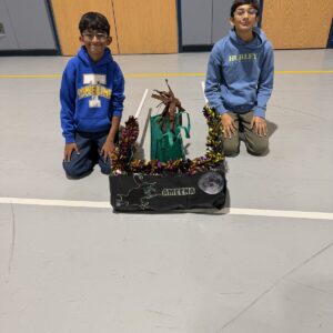 Child in a Witch costume on wheels with the Timberlane Middle School students who built it