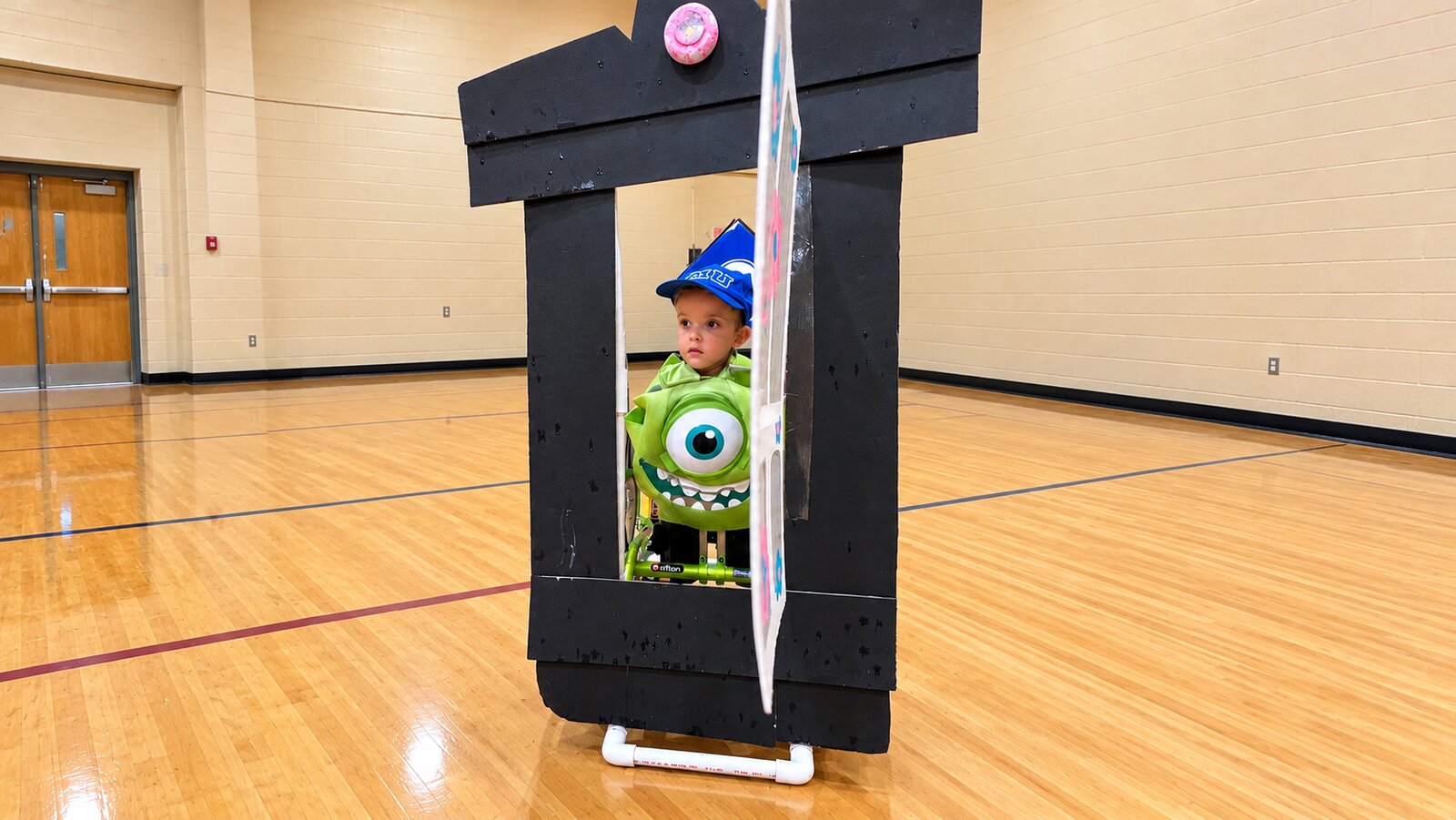Child in a Mike Wazowski costume on wheels