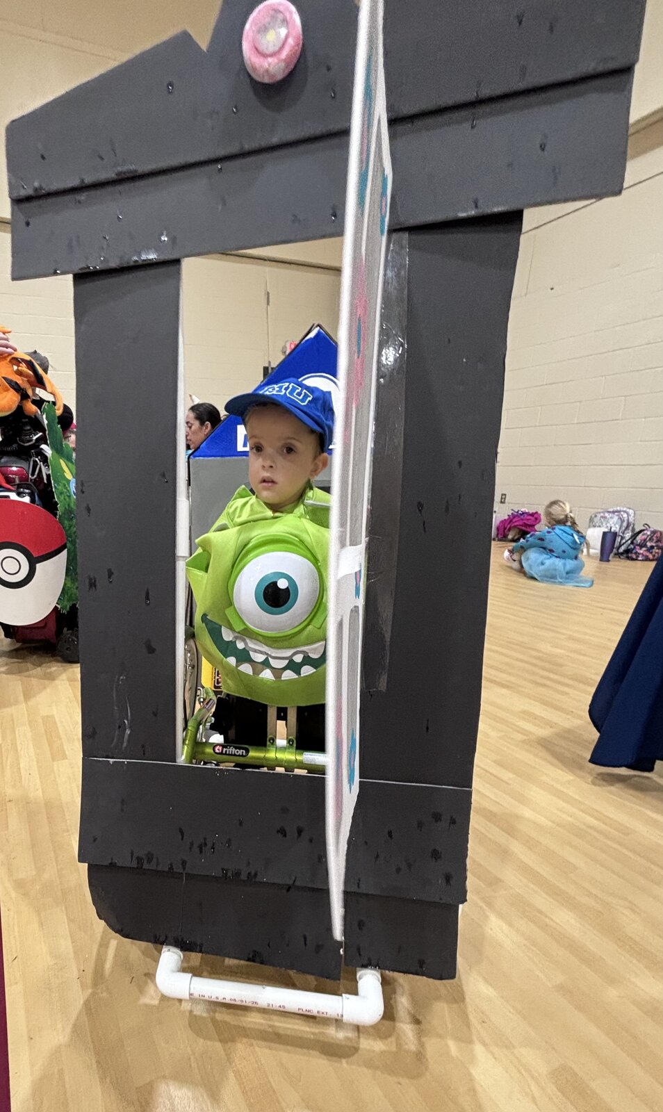 Child in a Mike Wazowski costume on wheels