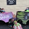 Children in Monster Truck Society costumes on wheels