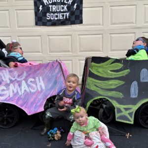 Children in Monster Truck Society costumes on wheels