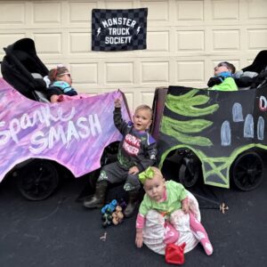 Children in Monster Truck Society costumes on wheels